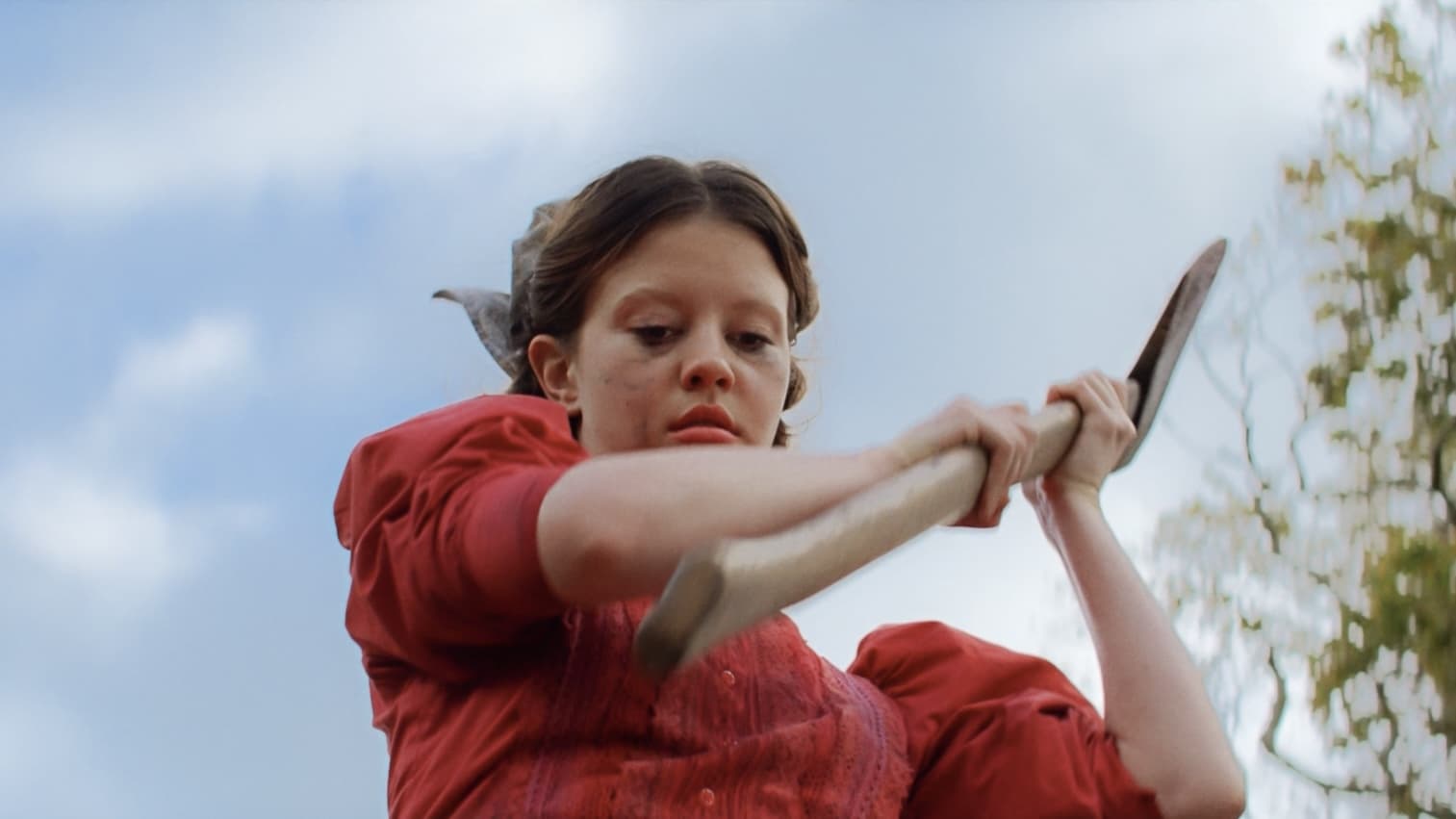 Mia Goth as Pearl holding an ax up about to swing