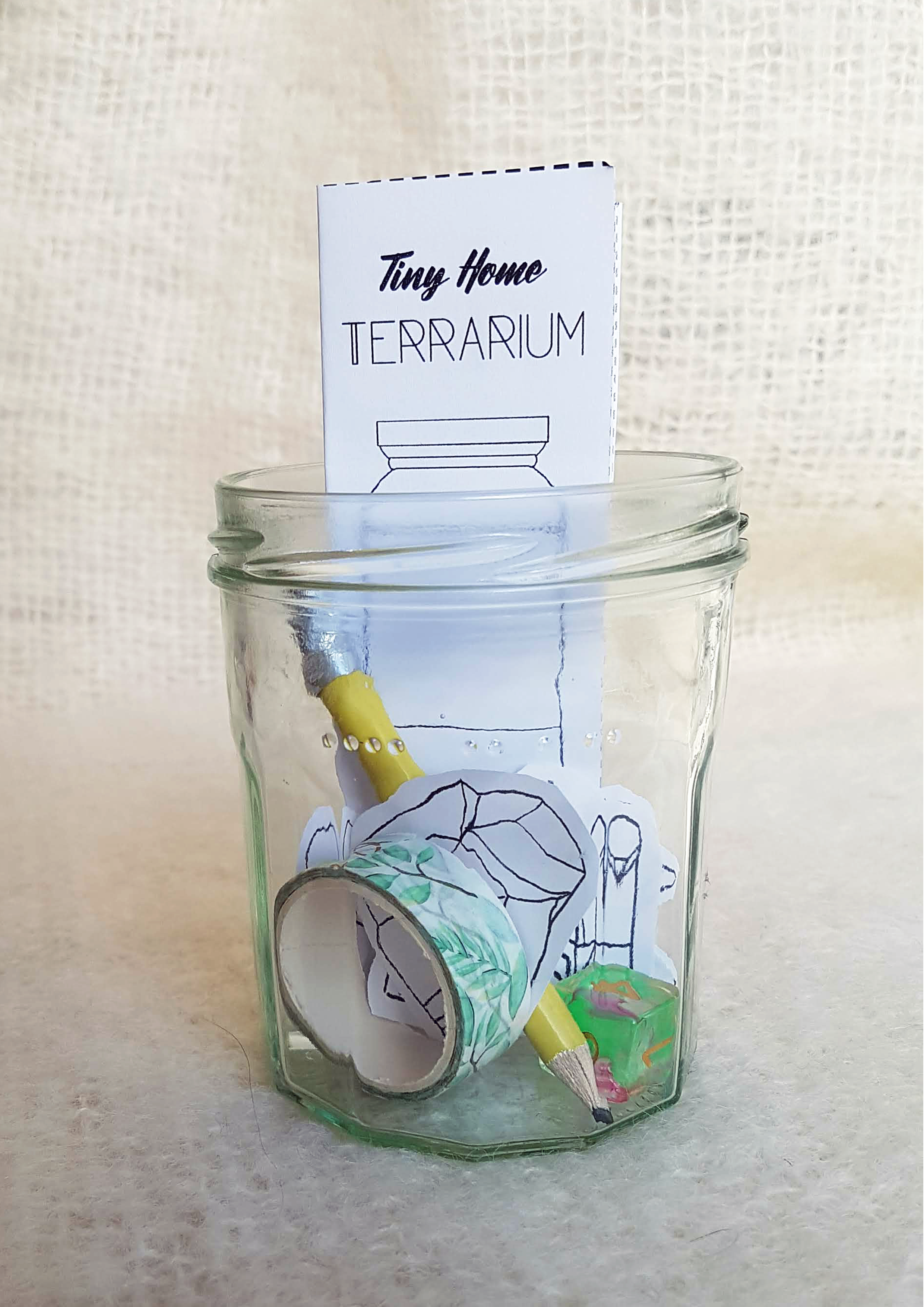 Tiny Home Terrarium game in a glass jam jar, featuring washi tape, a pencil, and a single die.