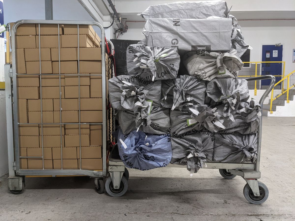 Crate with boxes and pushcart full of bags of things ready to be sent out.